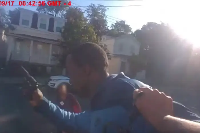 A still from police body cam footage showing Gregory Edwards holding a gun.